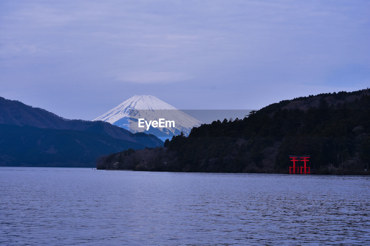 Scenic view of lake by snowcapped mountains against sky