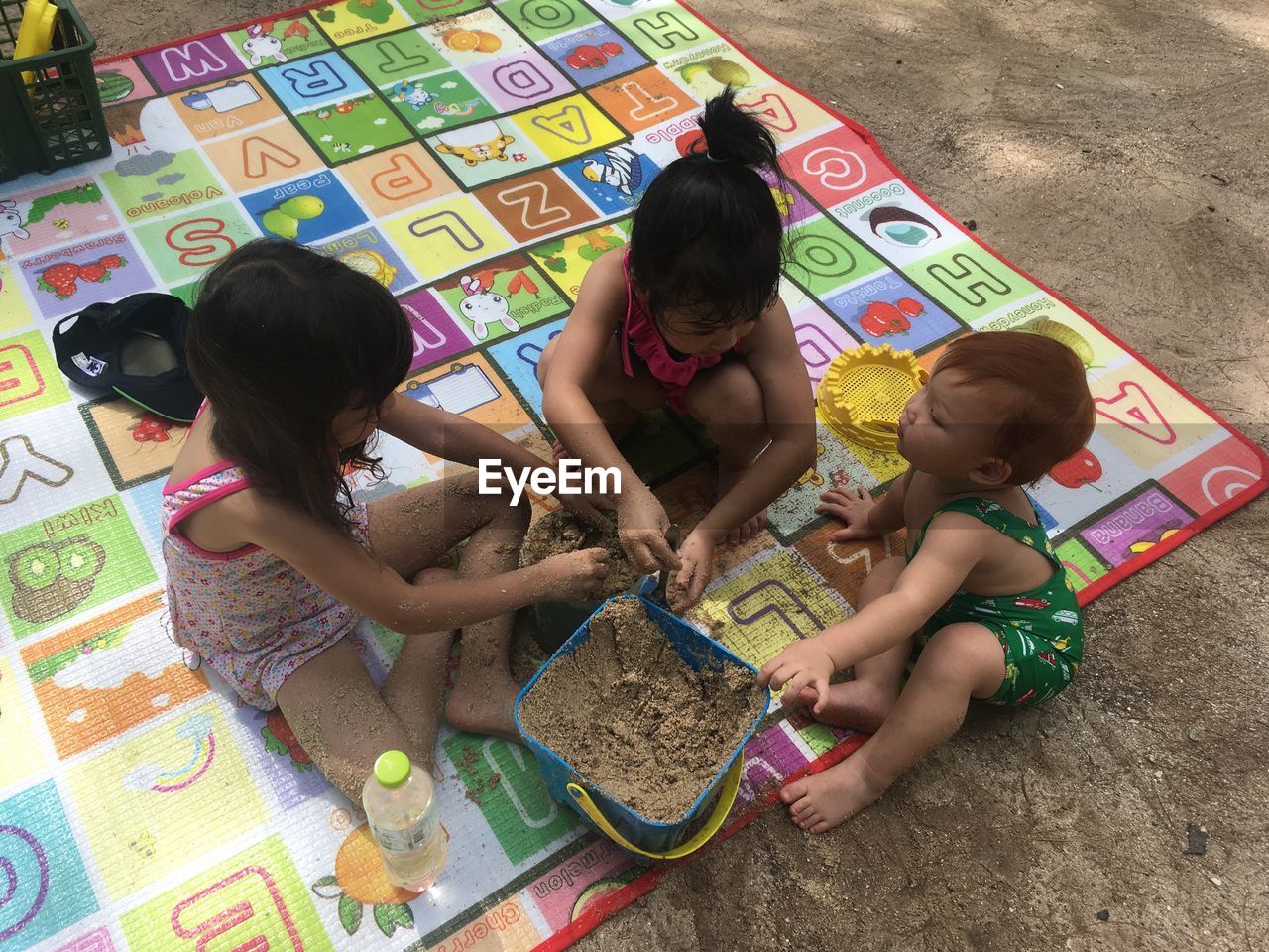 High angle view of friends playing with sand at playground