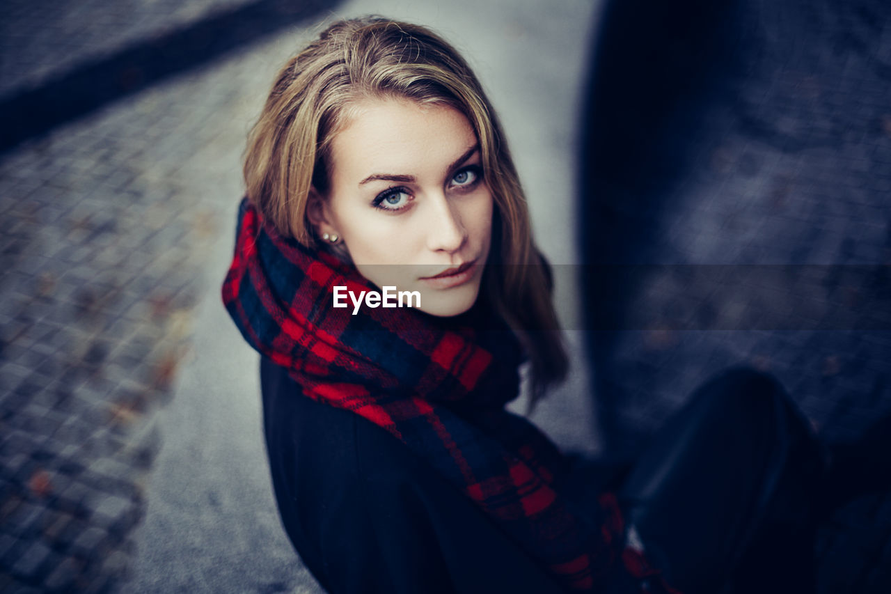 Portrait of young woman with scarf looking up at camera