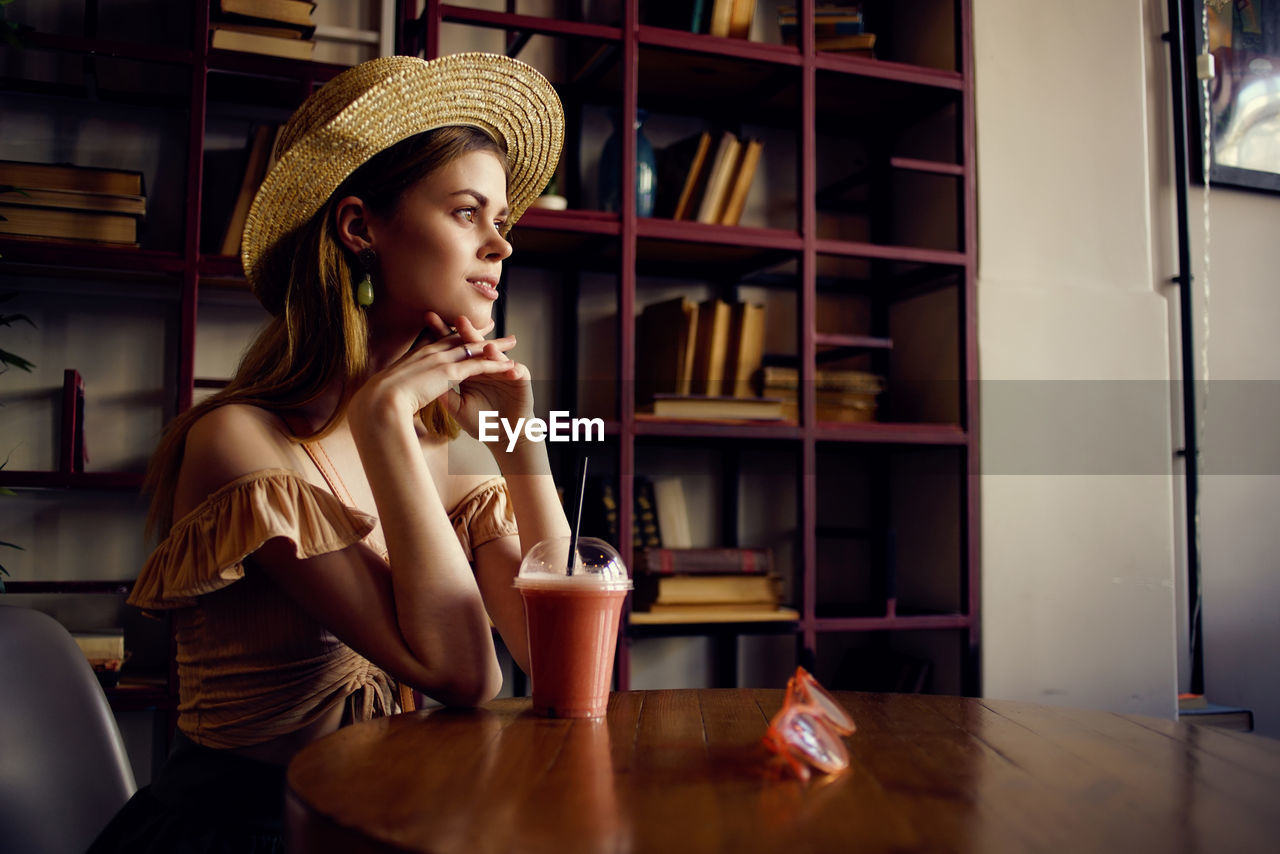 WOMAN LOOKING AWAY WHILE SITTING ON TABLE