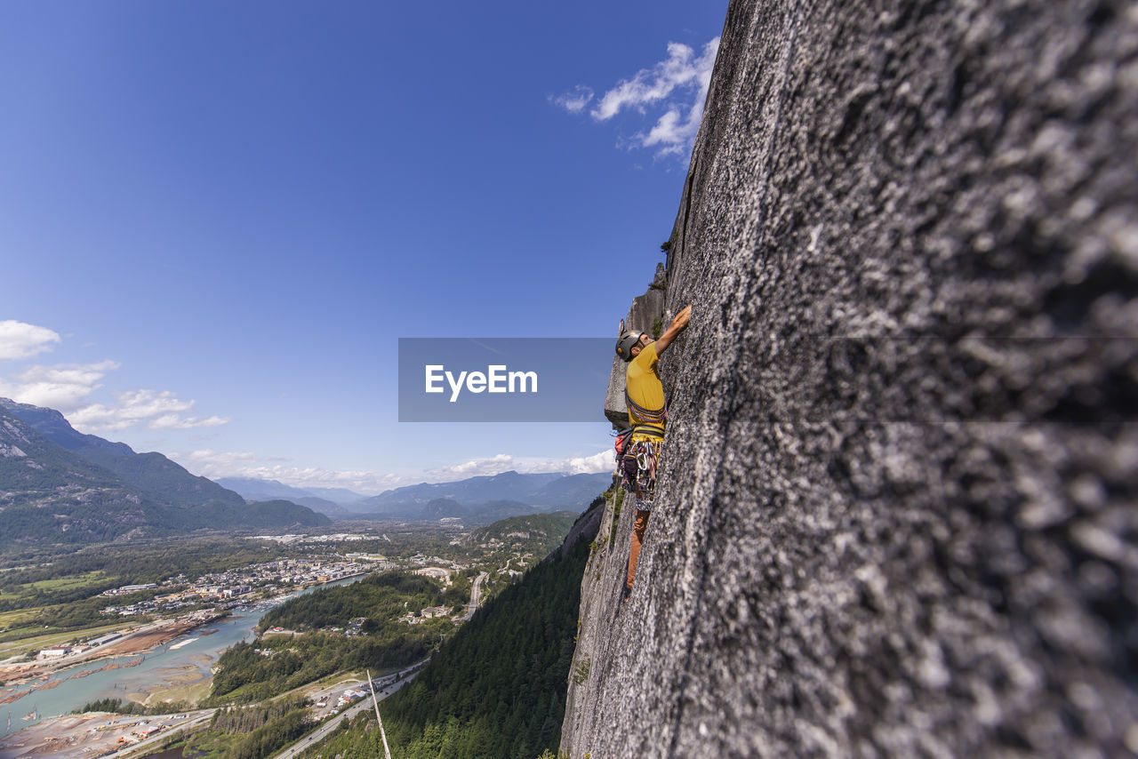 Side view man rock climbing squamish chief above the sea and highway