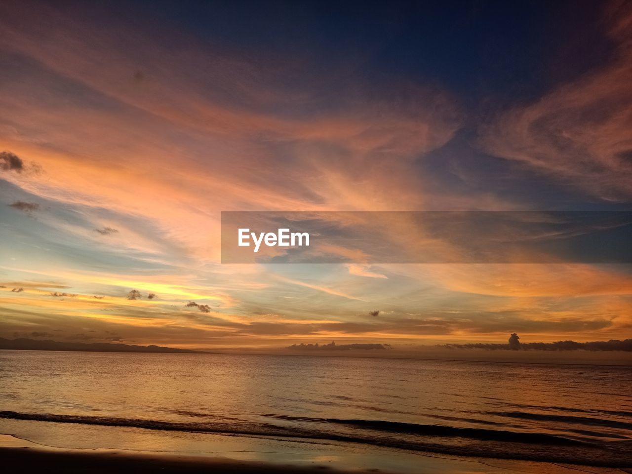 Scenic view of sea against dramatic sky during sunset