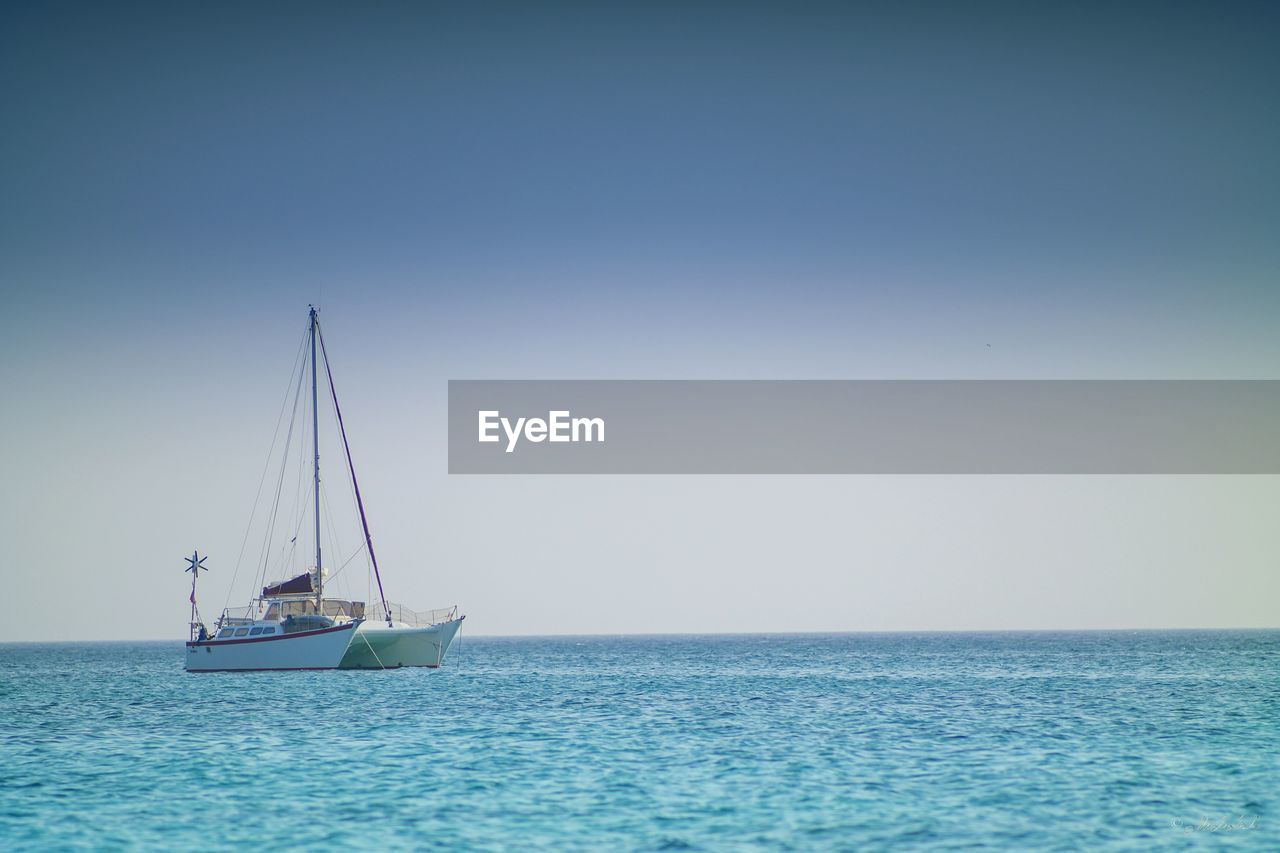 Catamaran sailing in sea against sky