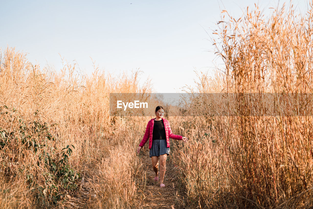 Woman walking on field against sky