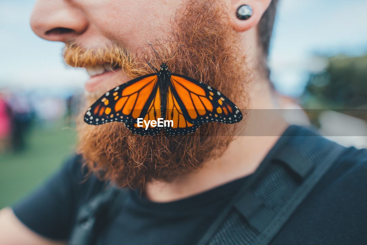 Midsection of man with butterfly on beard