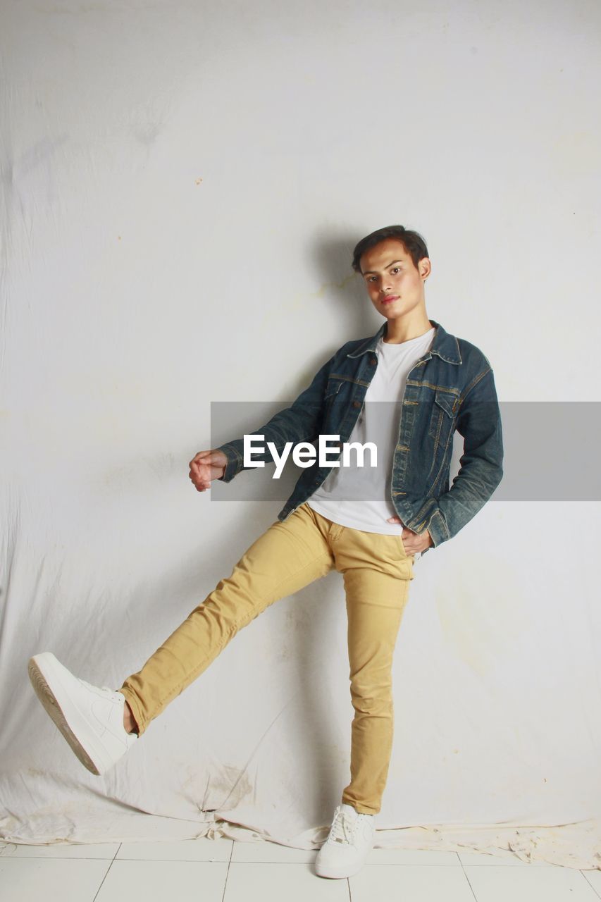 Portrait of young man standing against wall