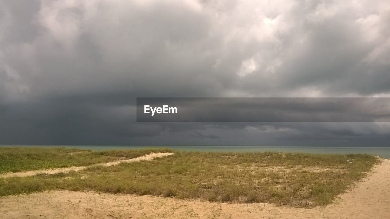 SCENIC VIEW OF FIELD AGAINST STORM CLOUDS OVER LANDSCAPE