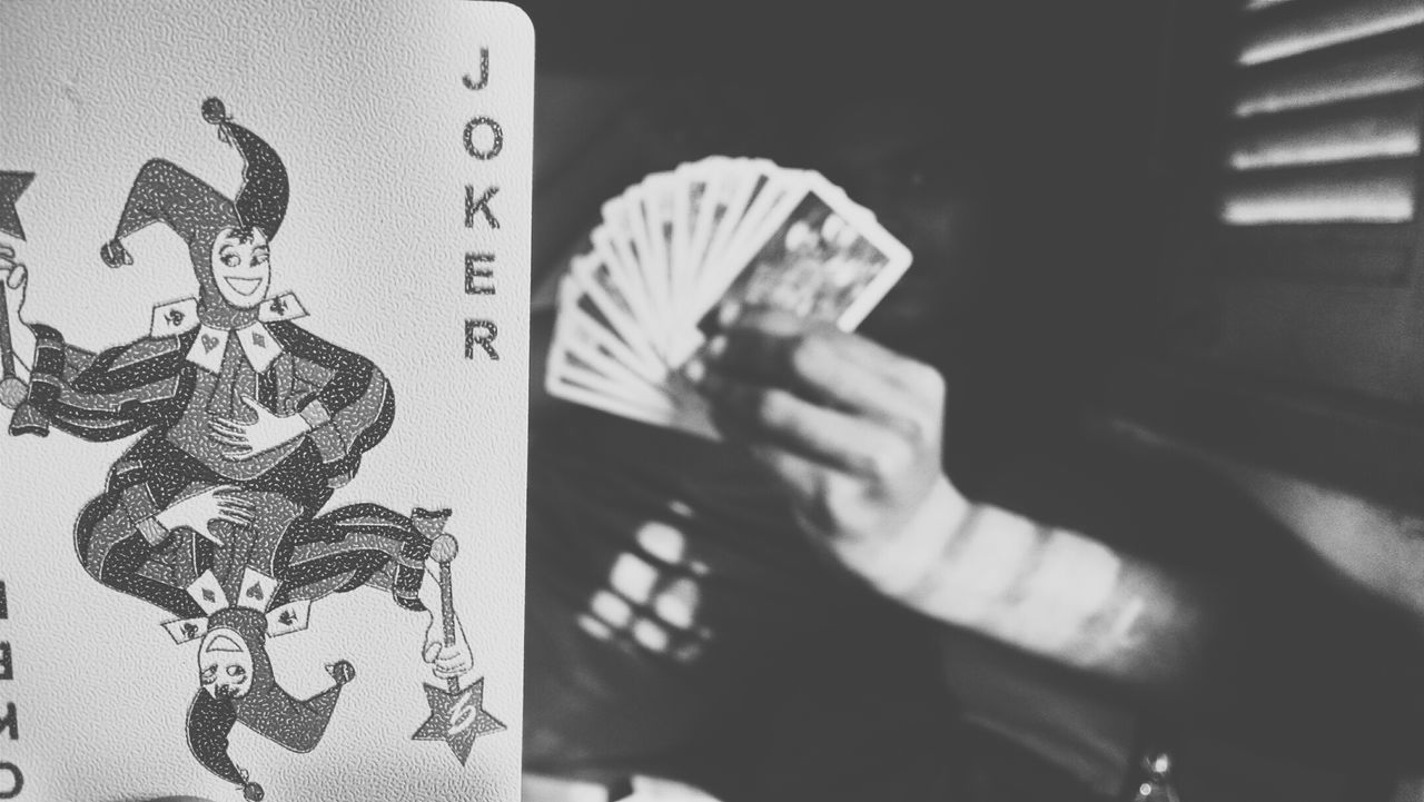 Close-up of joker card by man