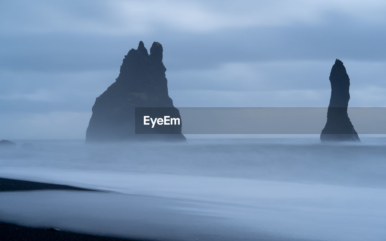 Scenic view of rocks on beach against sky