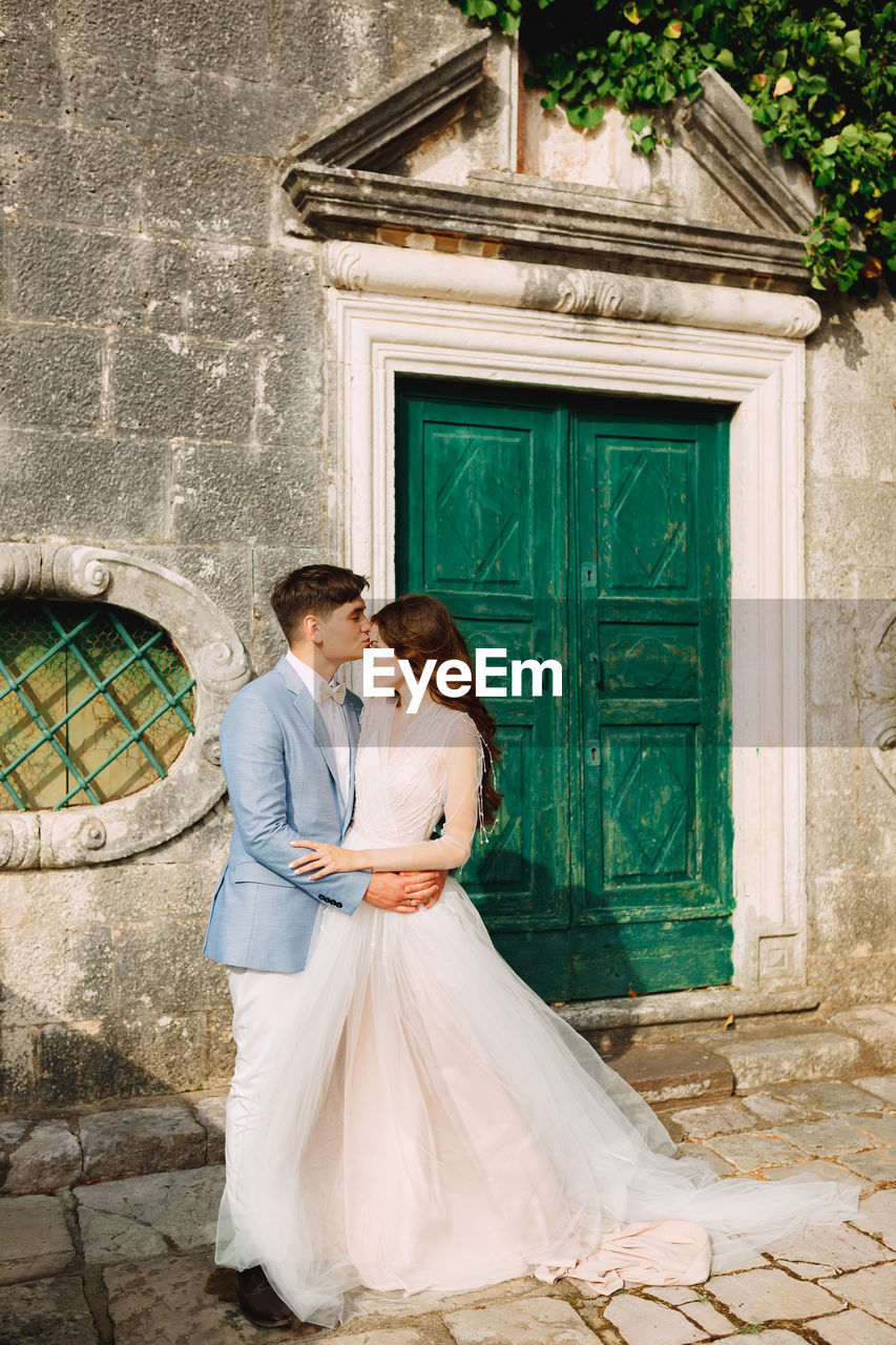 Bridegroom embracing while standing by door outdoors