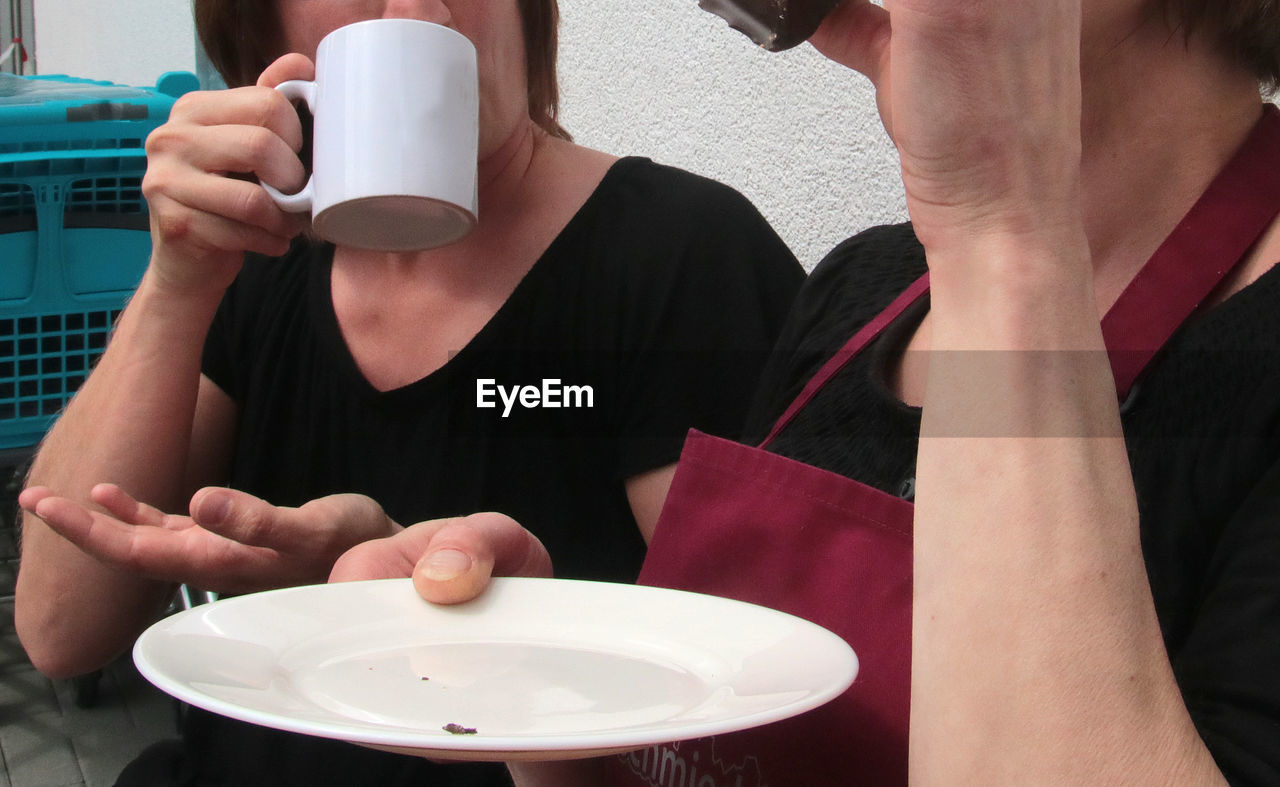 MIDSECTION OF MAN HOLDING COFFEE CUP AND TABLE