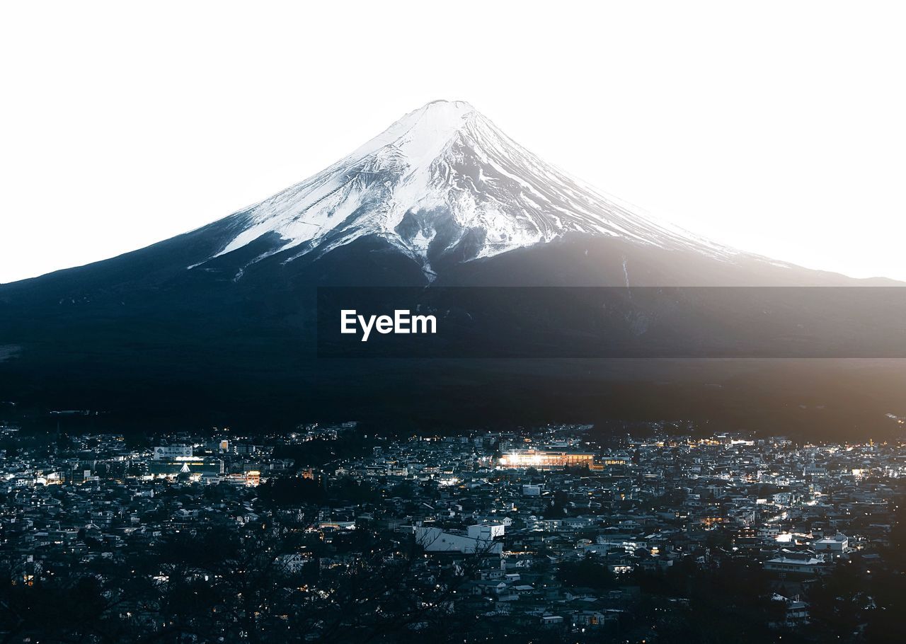 Snowcapped mountain and cityscape against sky