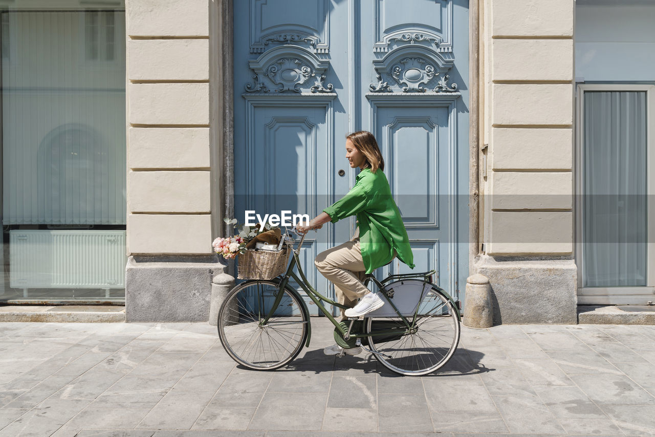 Woman riding bicycle on footpath at sunny day