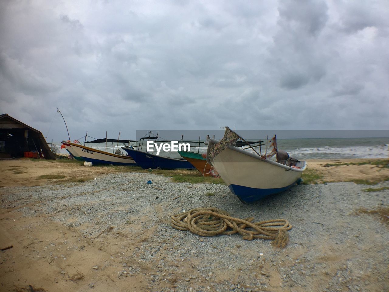 BOATS MOORED ON BEACH AGAINST SKY