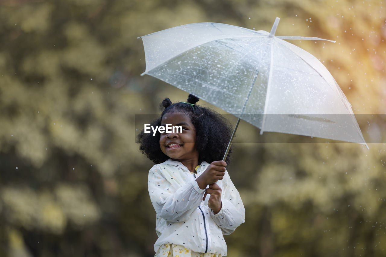 portrait of smiling young woman with umbrella standing outdoors