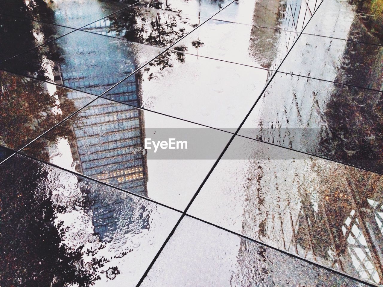 Skyscrapers reflected on wet street in rainy season