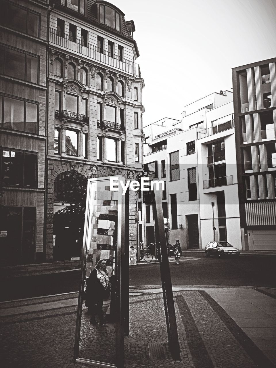 Reflection of woman in mirror with city buildings in background