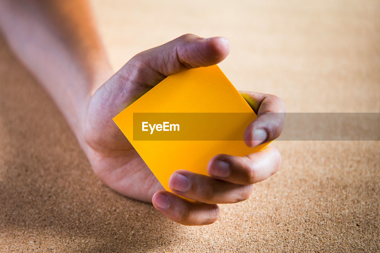 Close-up of person holding orange paper