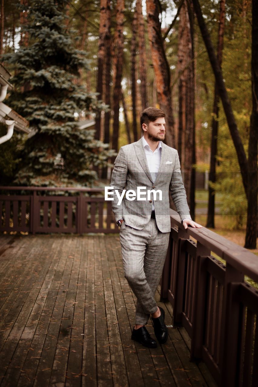 Thoughtful businessman standing against trees