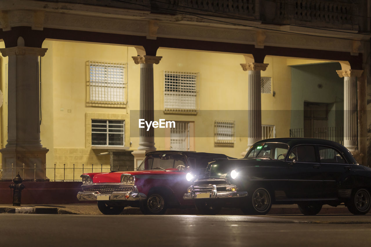 CARS PARKED ON STREET AGAINST ILLUMINATED BUILDINGS