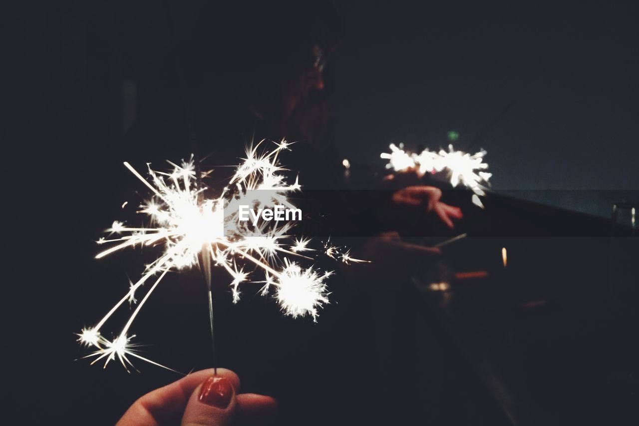 Woman hand with fireworks at night