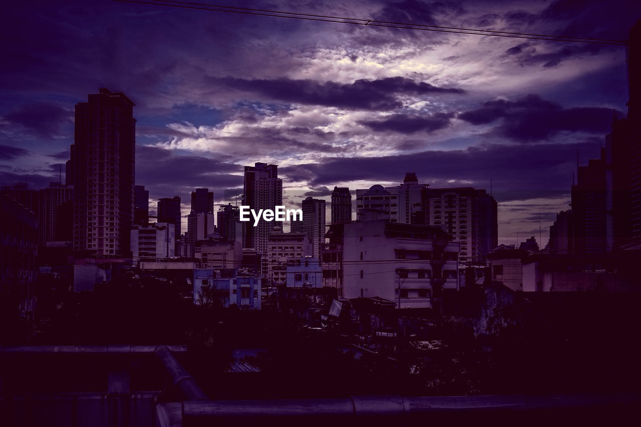 Cityscape against cloudy sky at dusk