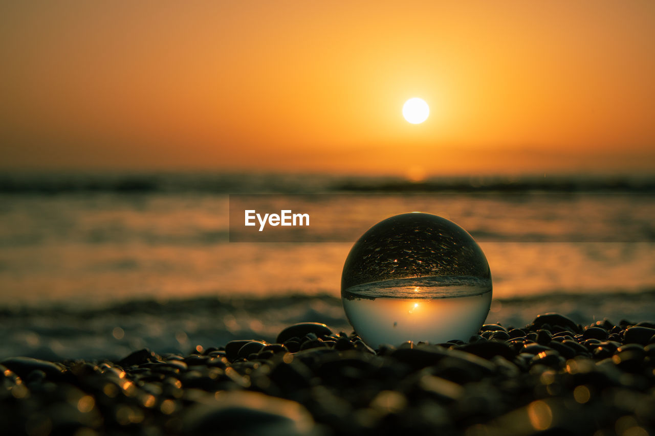 CLOSE-UP OF CRYSTAL BALL ON SHORE