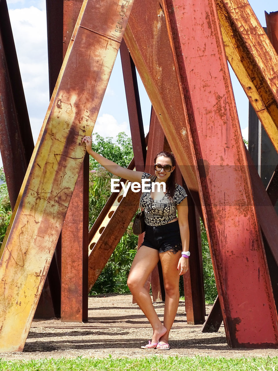 Full length portrait of woman standing against built metallic structure