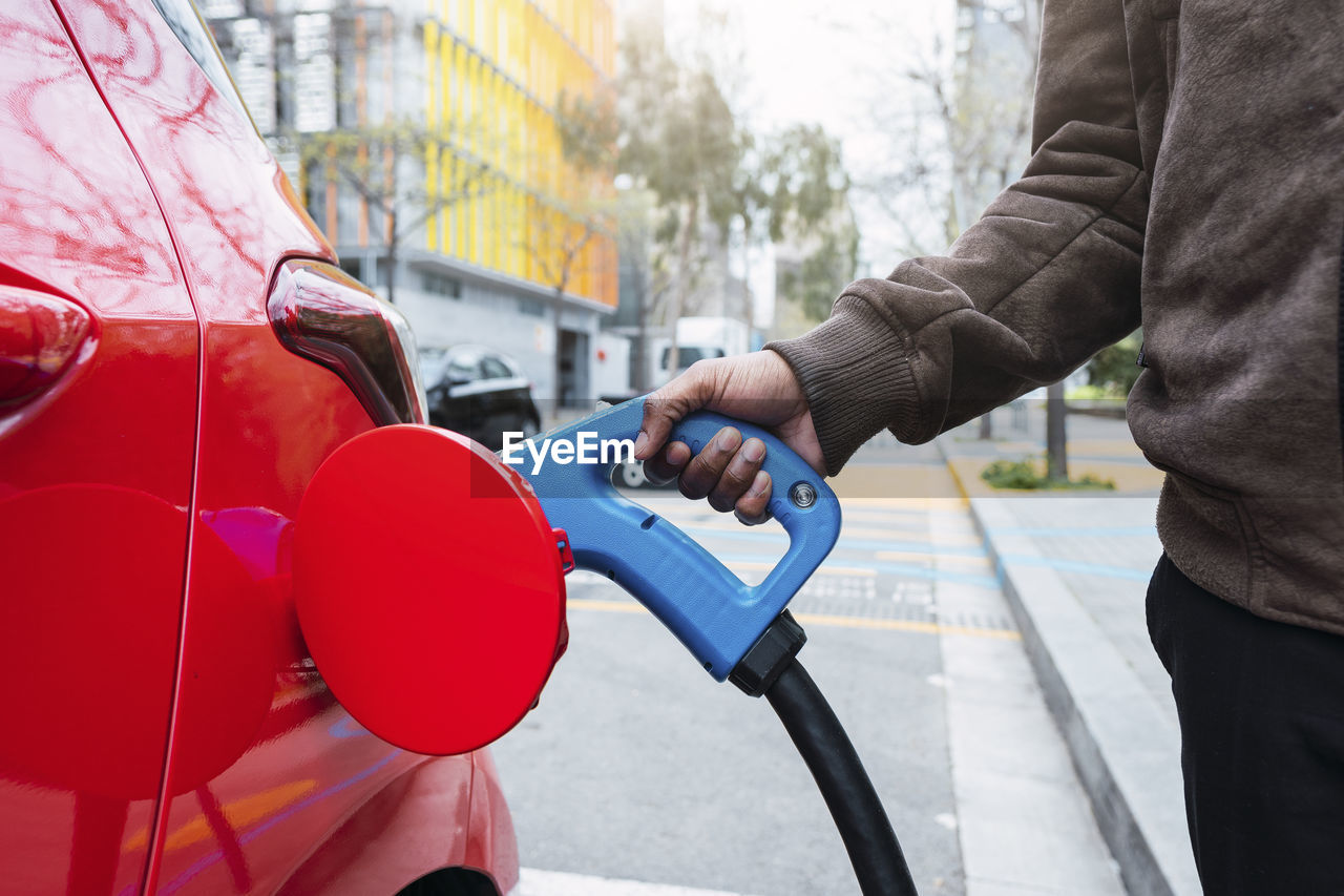 Hand of man charging car at electric station