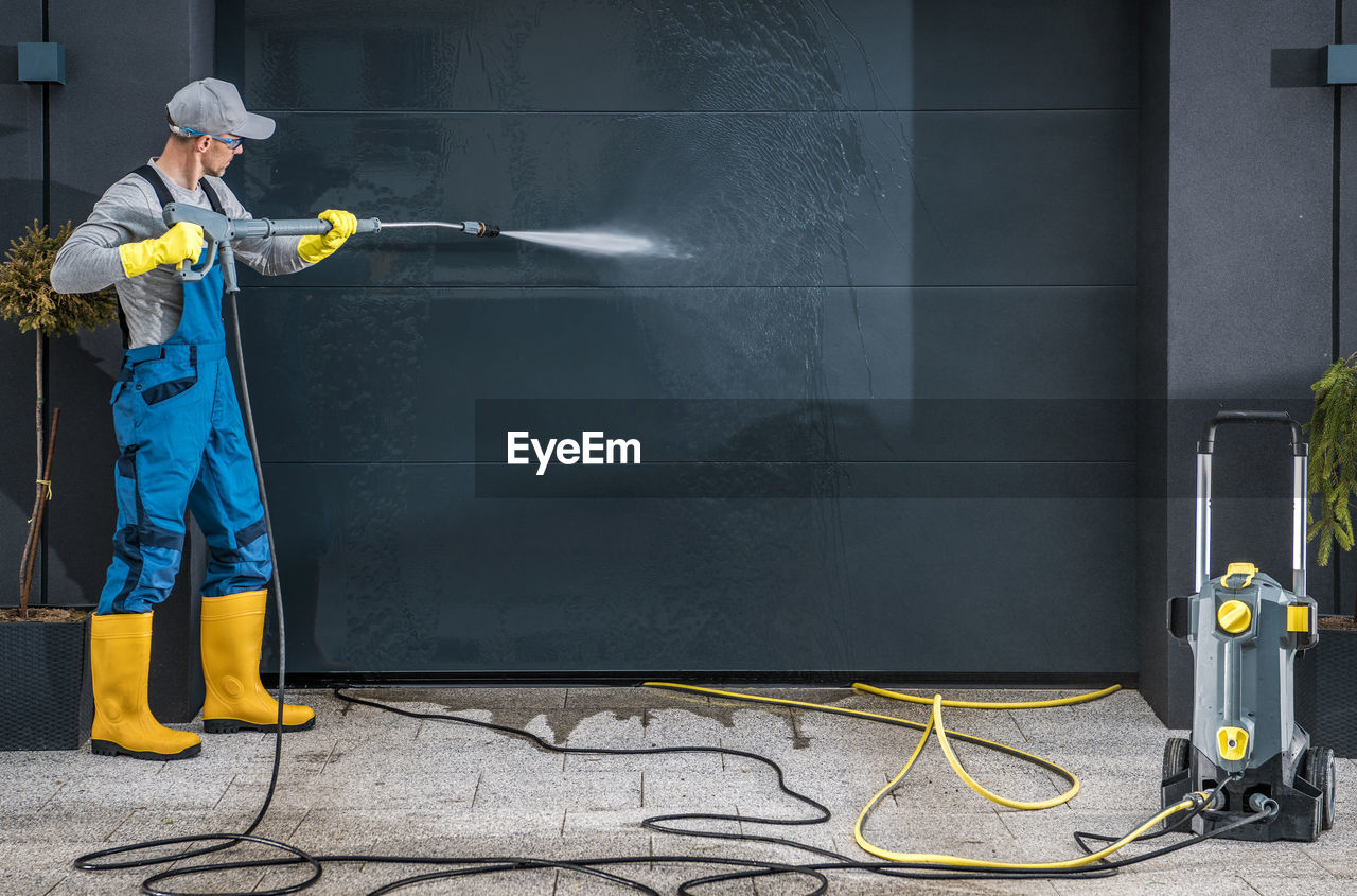 Mature man cleaning garage shutter outdoors