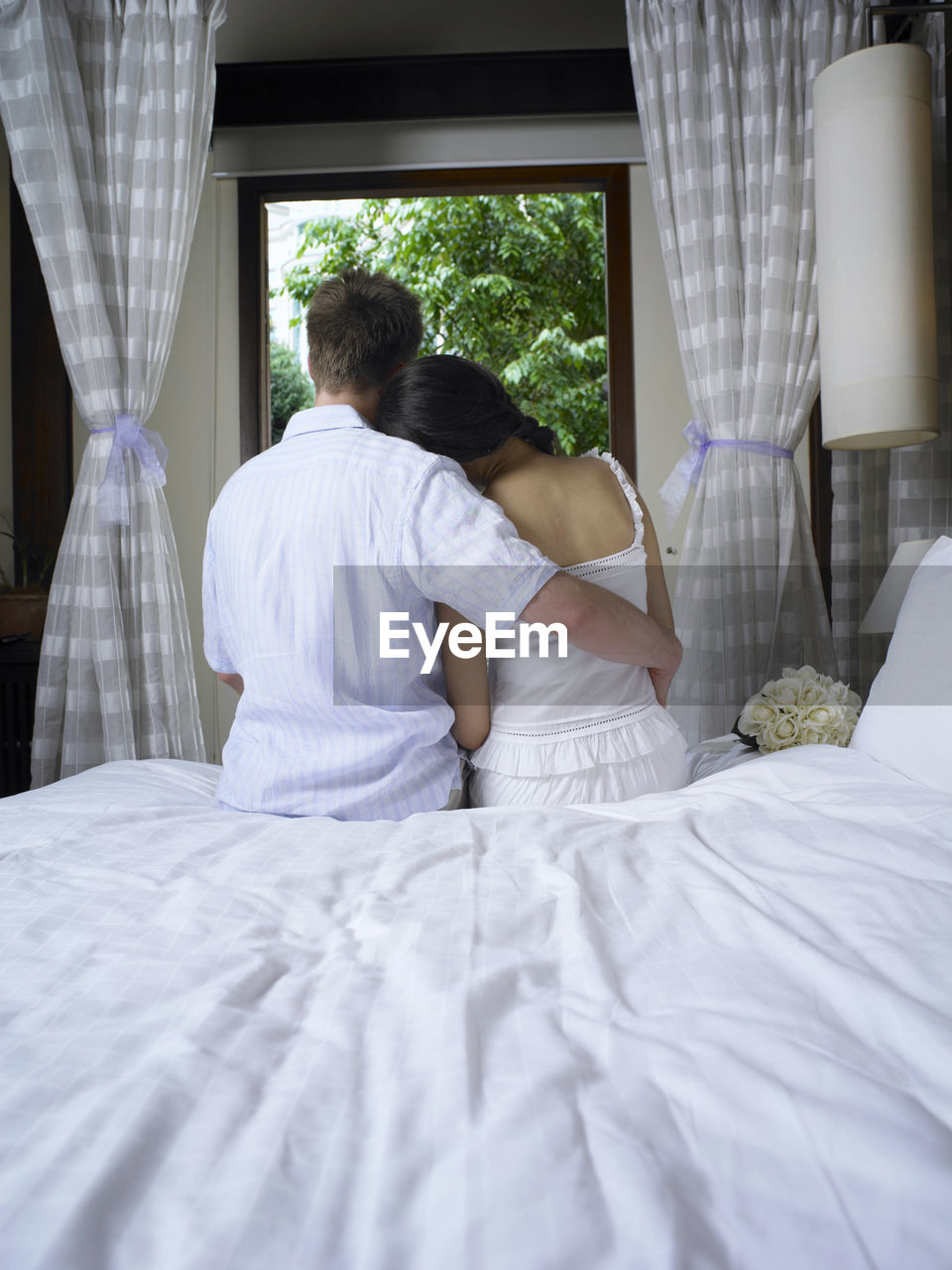 Rear view of couple relaxing on bed