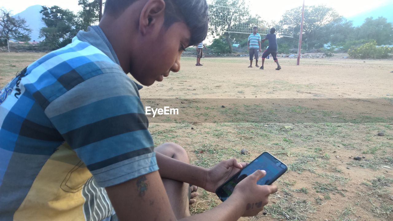 CLOSE-UP OF MAN USING MOBILE PHONE IN PARK