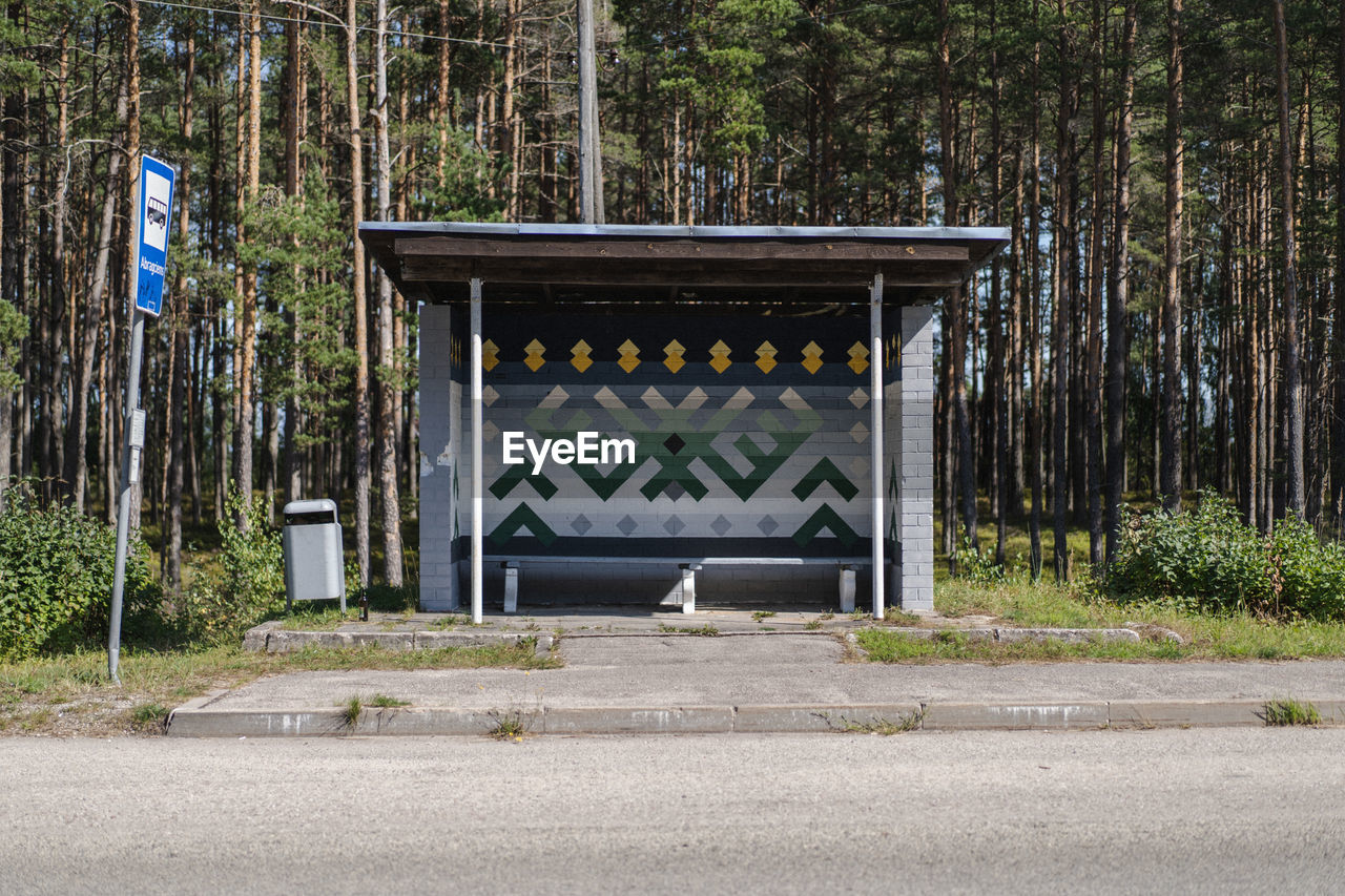 Traditional latvian symbols on the bus stop on road by trees in forest