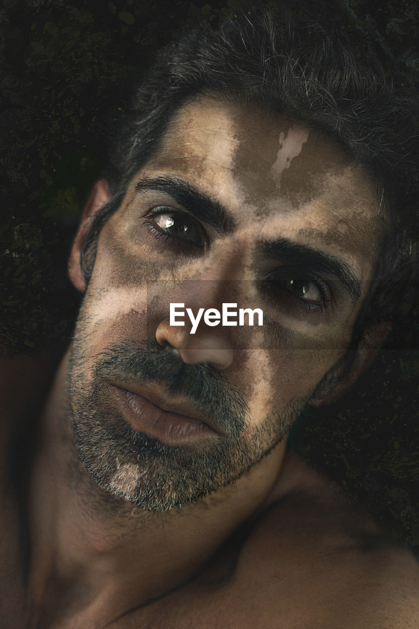 Close-up portrait of man with face paint against black background