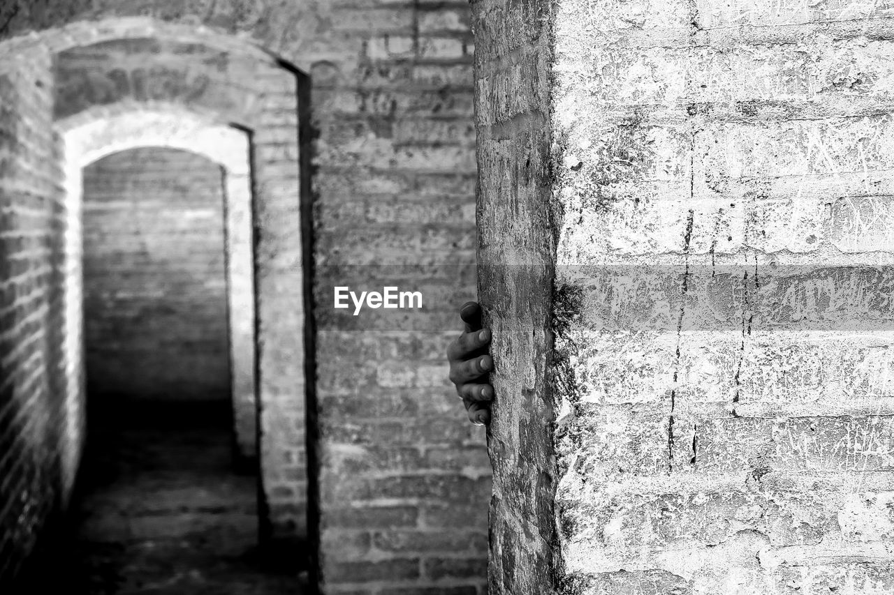 Cropped hand touching brick wall in at old ruin