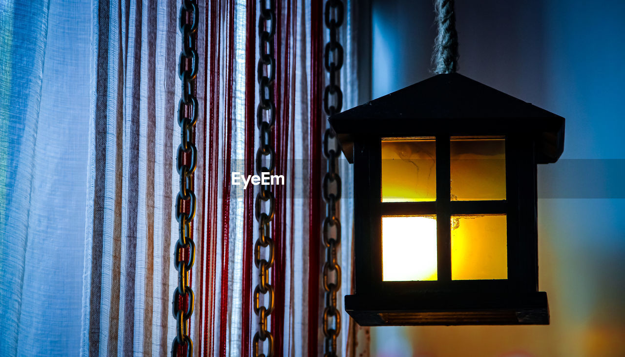 Close-up of illuminated lamp against building