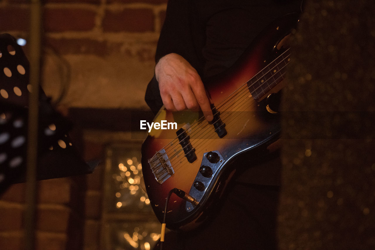 Midsection of man playing guitar on stage