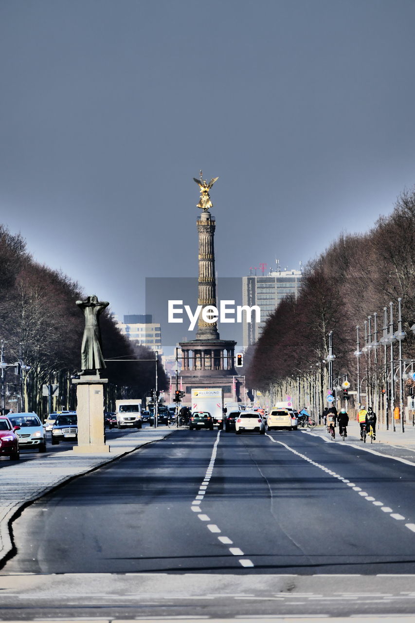 Victory column on street in city against cloudy sky