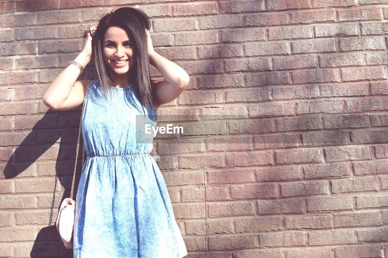 PORTRAIT OF YOUNG WOMAN STANDING OUTDOORS