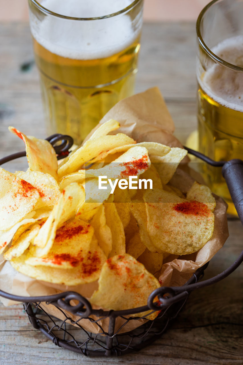 High angle view of fresh crunchy potato chips with beer on table