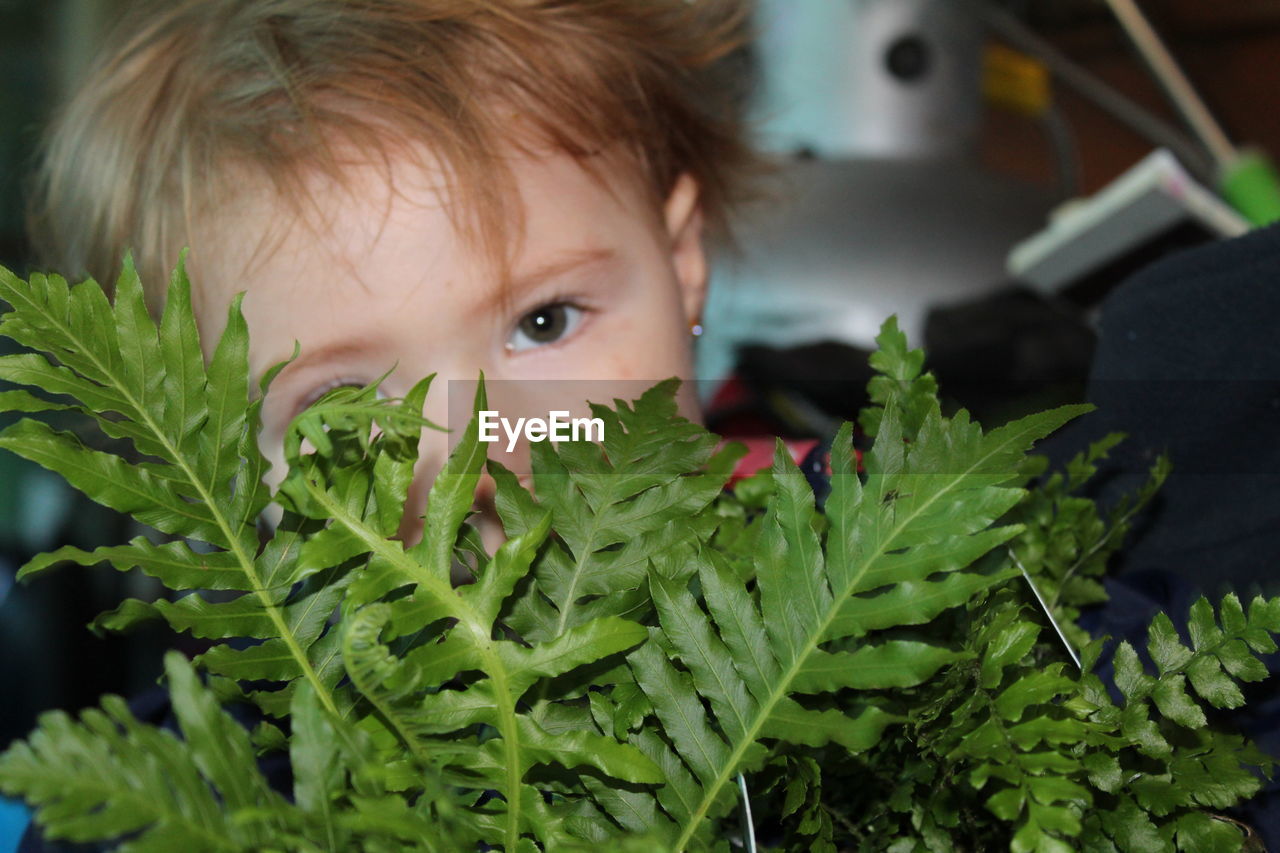 Portrait of girl hiding behind plant