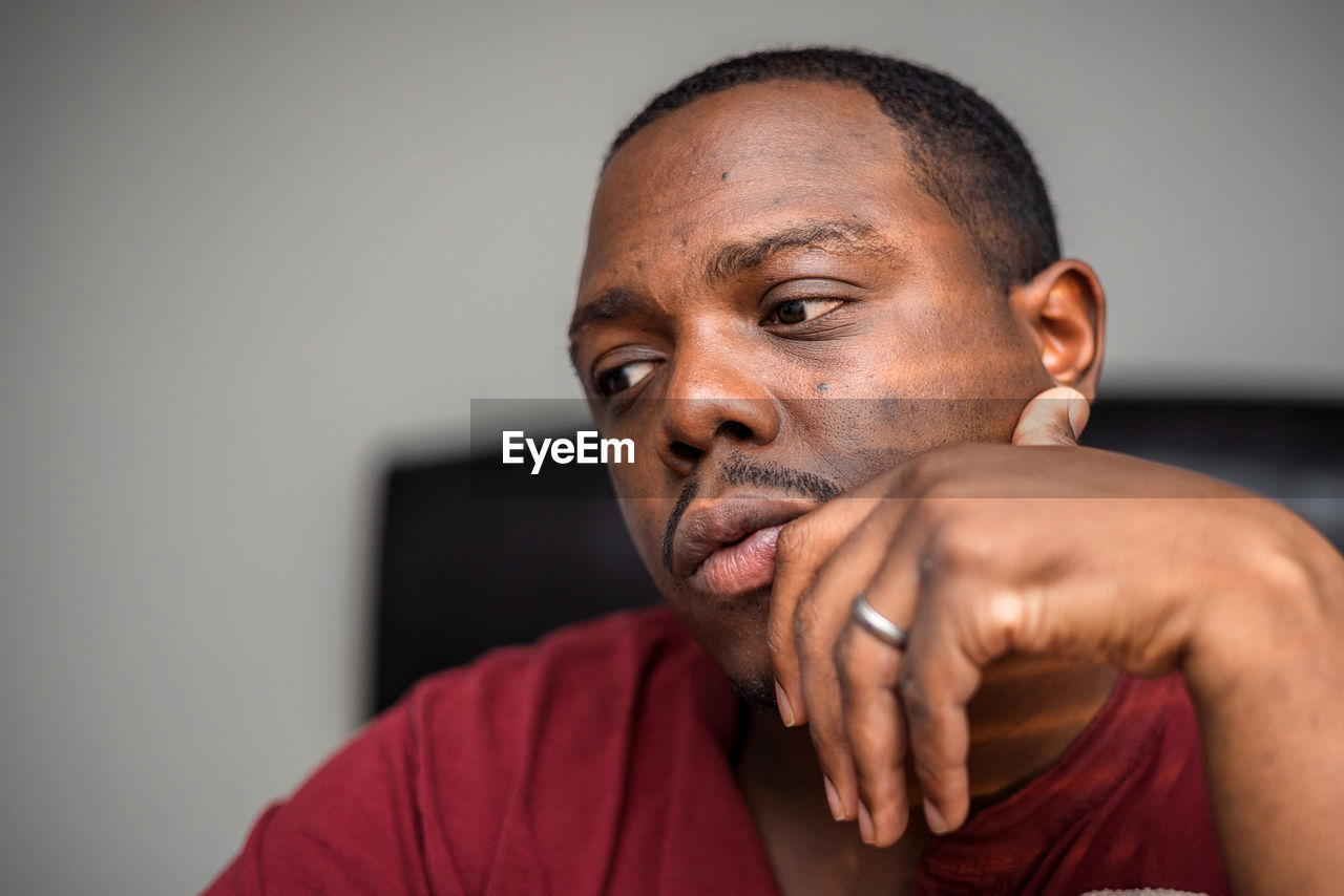 Young depressed or anxious african american man in bedroom at home sitting