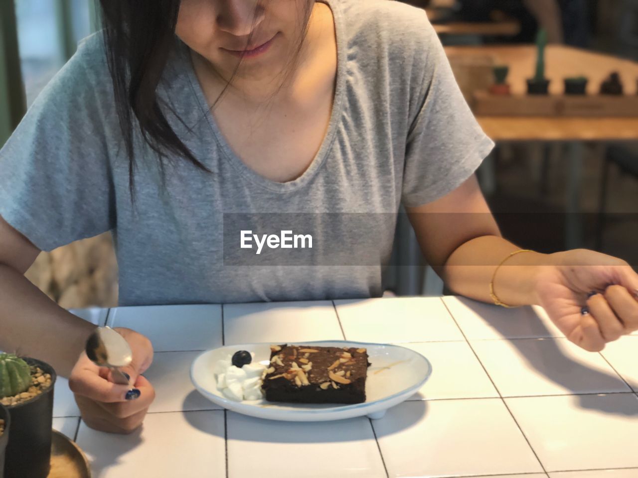 Midsection of woman having chocolate cake at table in restaurant