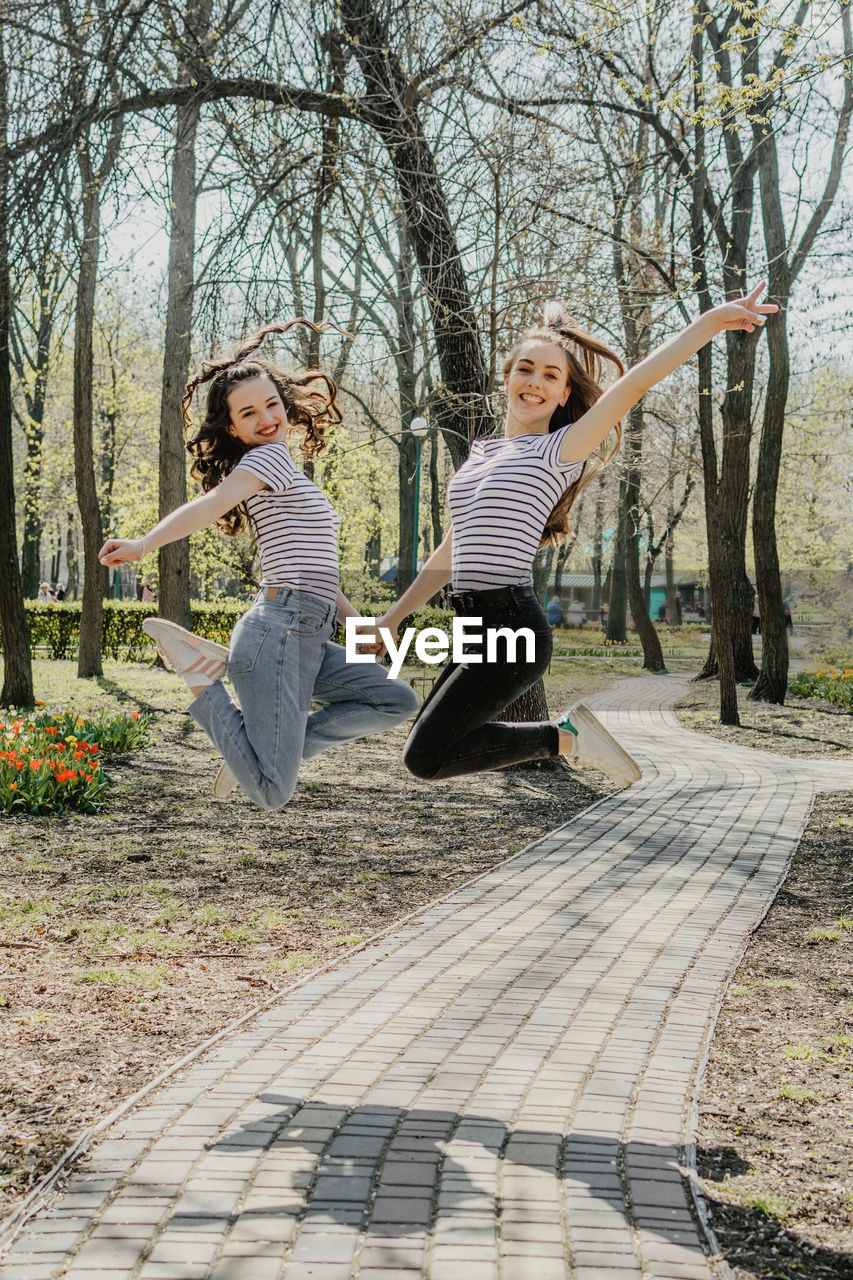 Happy siblings playing on plant against trees