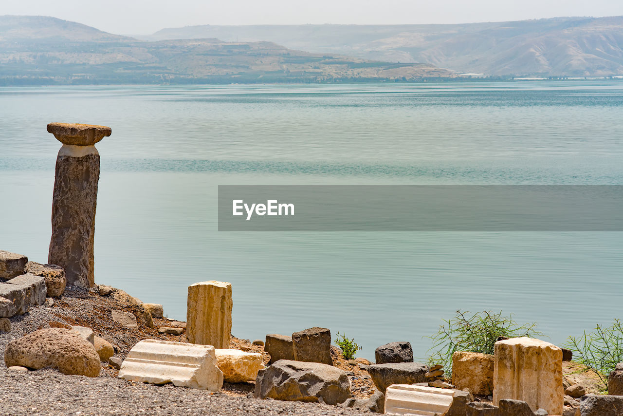 WOODEN POSTS ON SEA AGAINST SKY