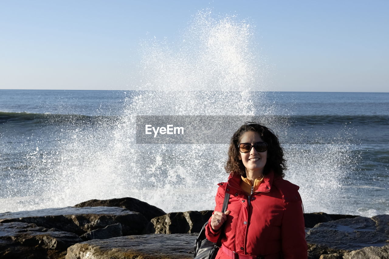 Portrait of woman in sunglasses standing at beach