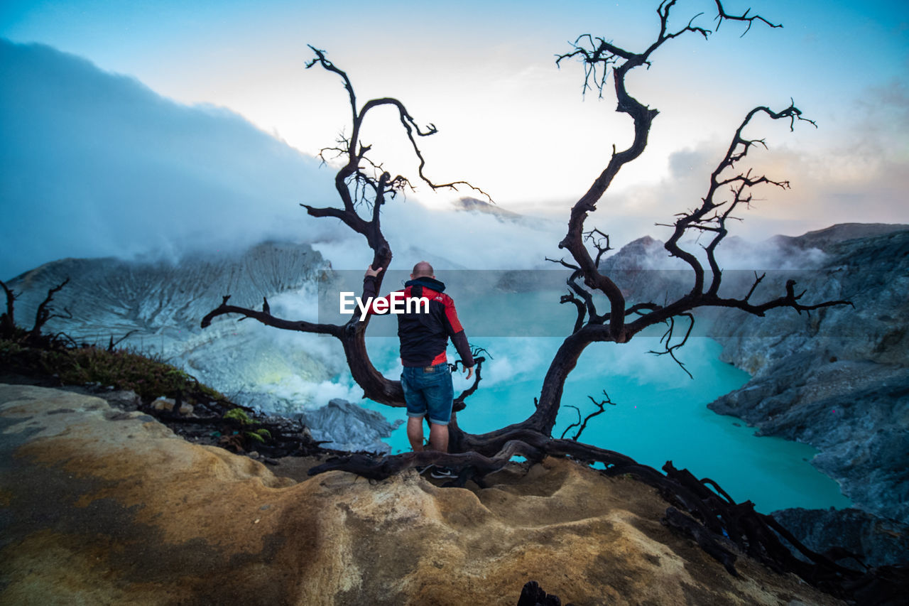 MAN ON ROCK BY MOUNTAINS