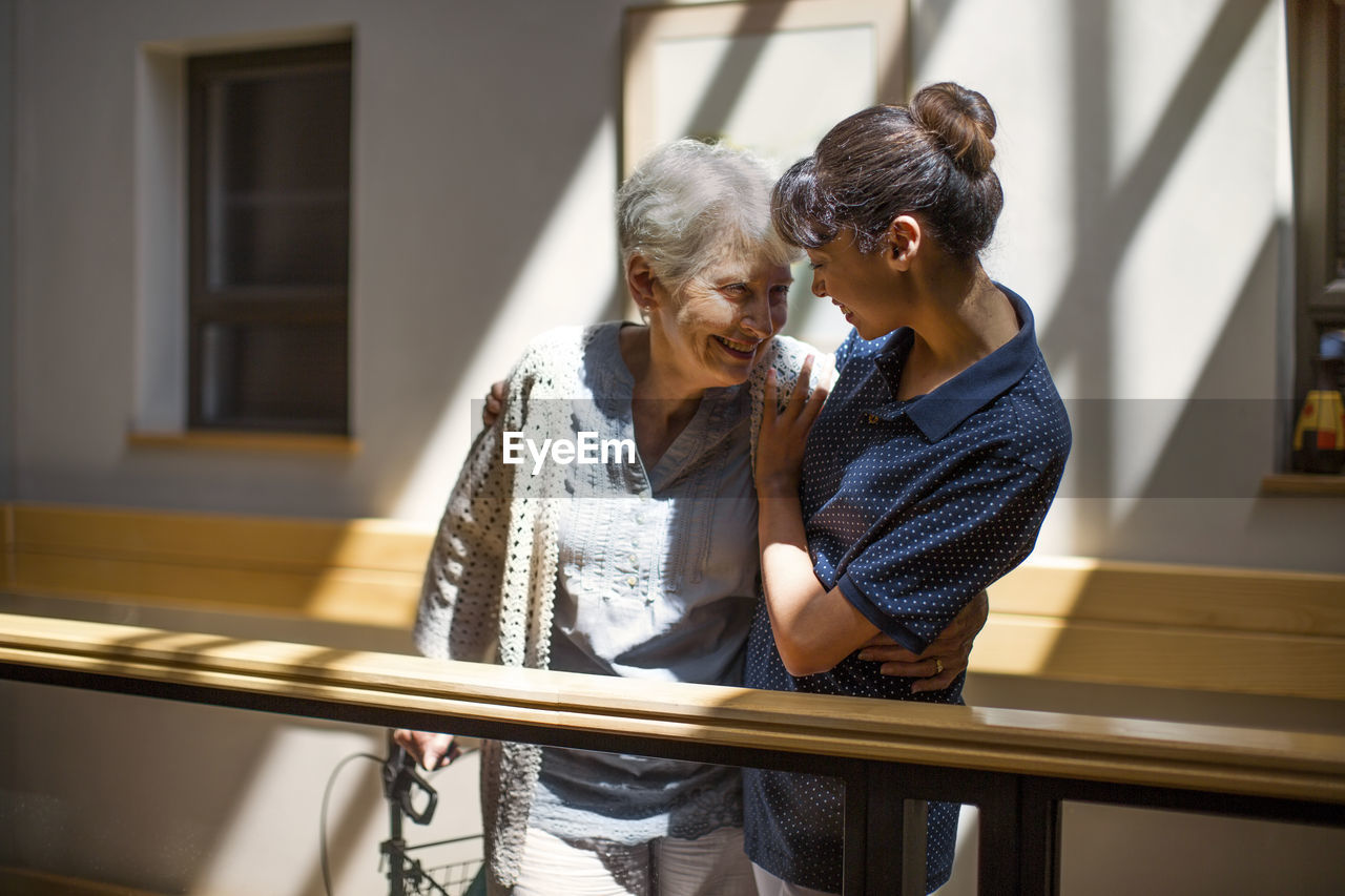 Nurse embracing senior woman in retirement home