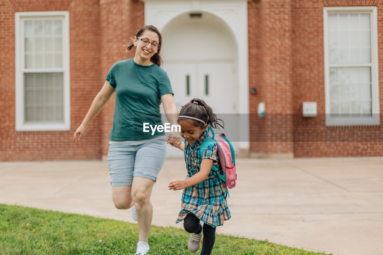 Young millennial mother sending daughter off back to school