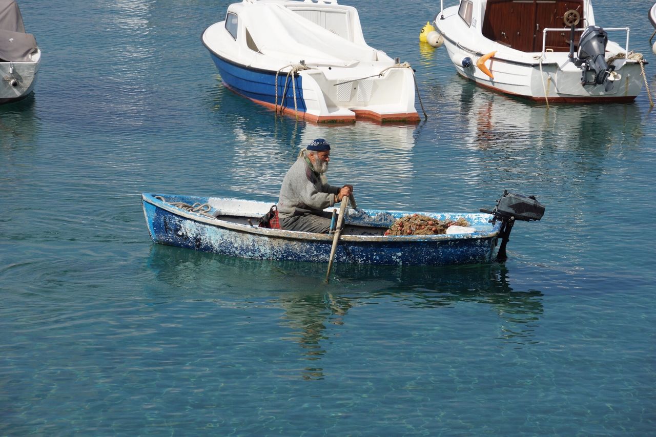 MAN IN BOAT SAILING IN WATER